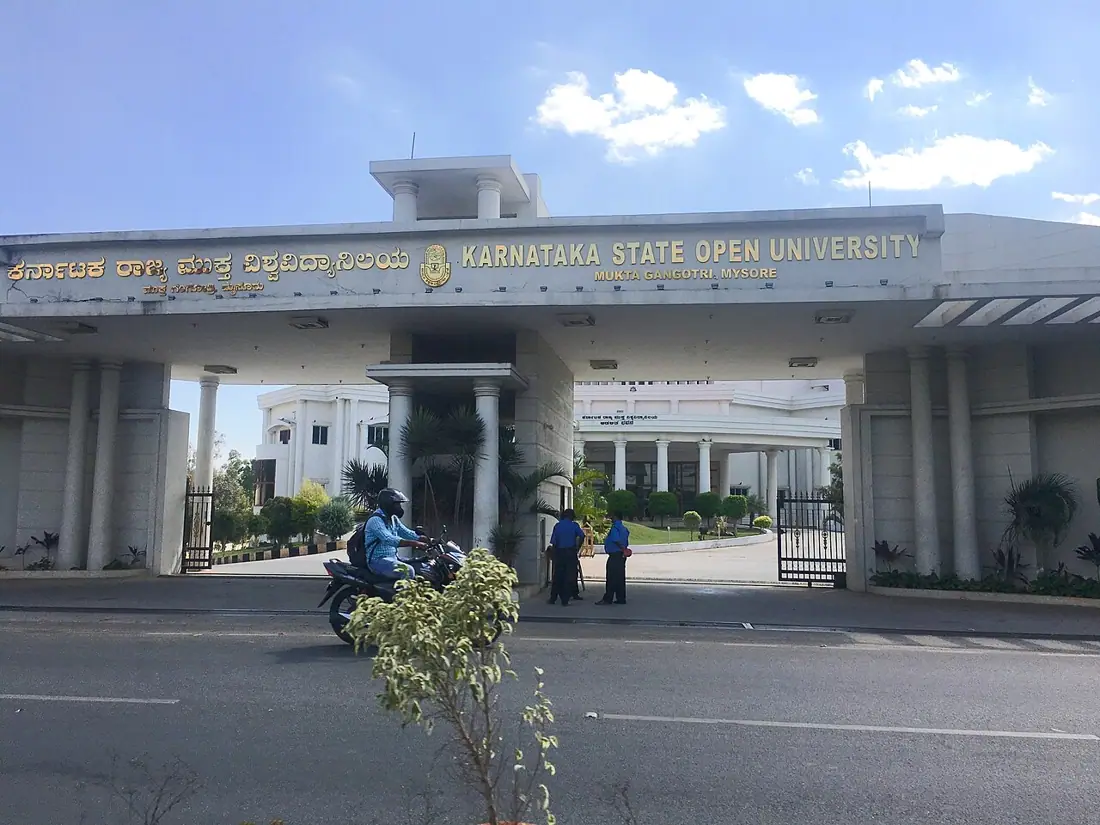 The main gate of KSOU, with its name, buildings, and a road.